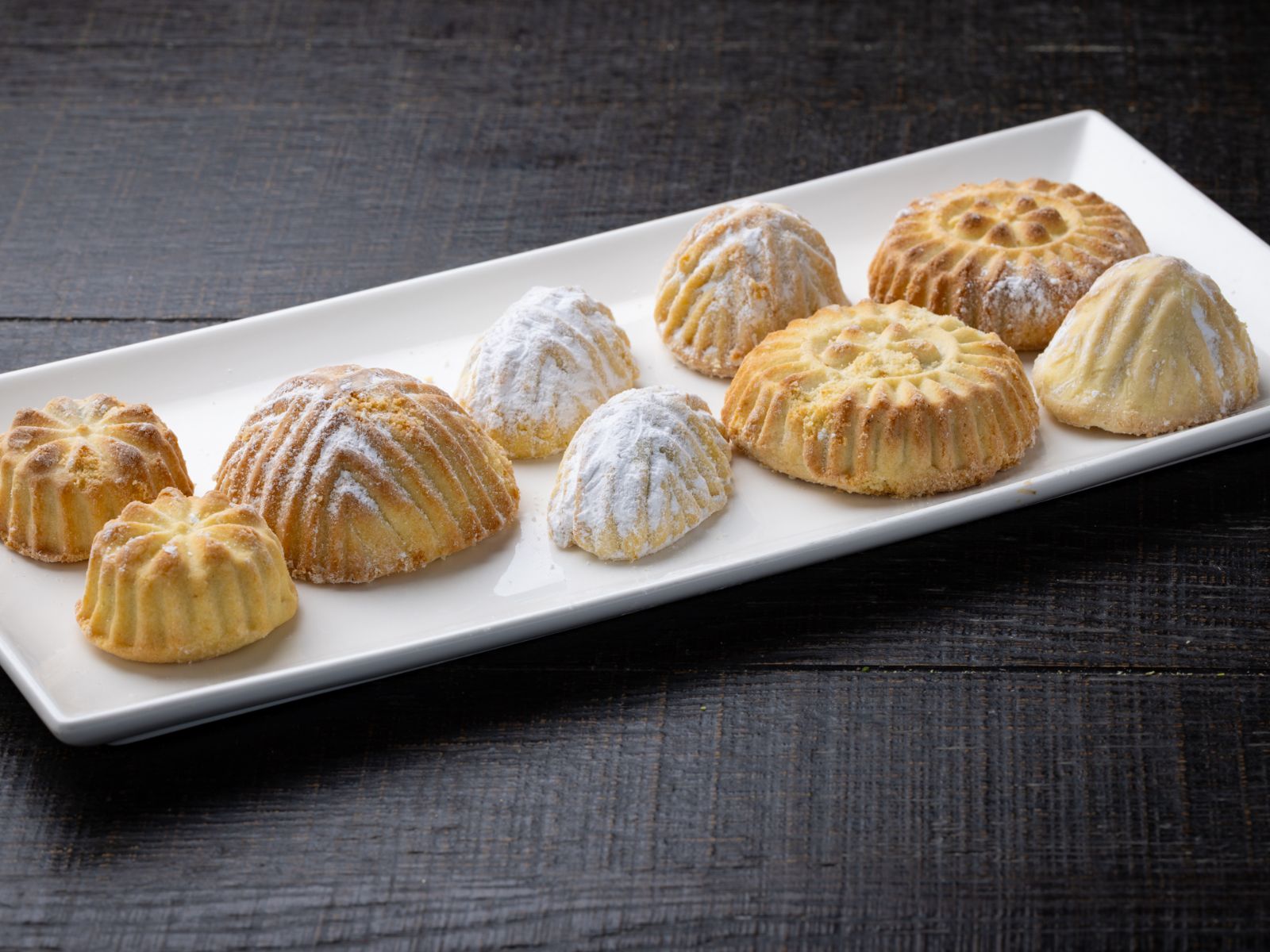 Moulded ma'amoul and sugar-dusted cookies on a white platter